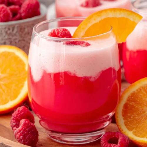 Sherbet party punch in a glass with orange slice and raspberry garnish