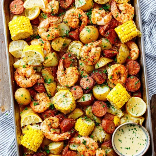 Shrimp boil with potatoes, corn, sausage, and lemon on a baking sheet