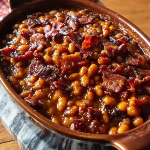 Southern baked beans with bacon in a ceramic dish, topped with crispy bacon bits