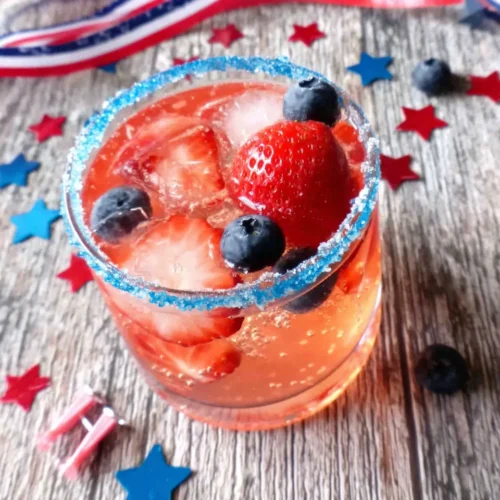 Sparkling vodka cocktail with berries in a glass with blue rim and star decorations