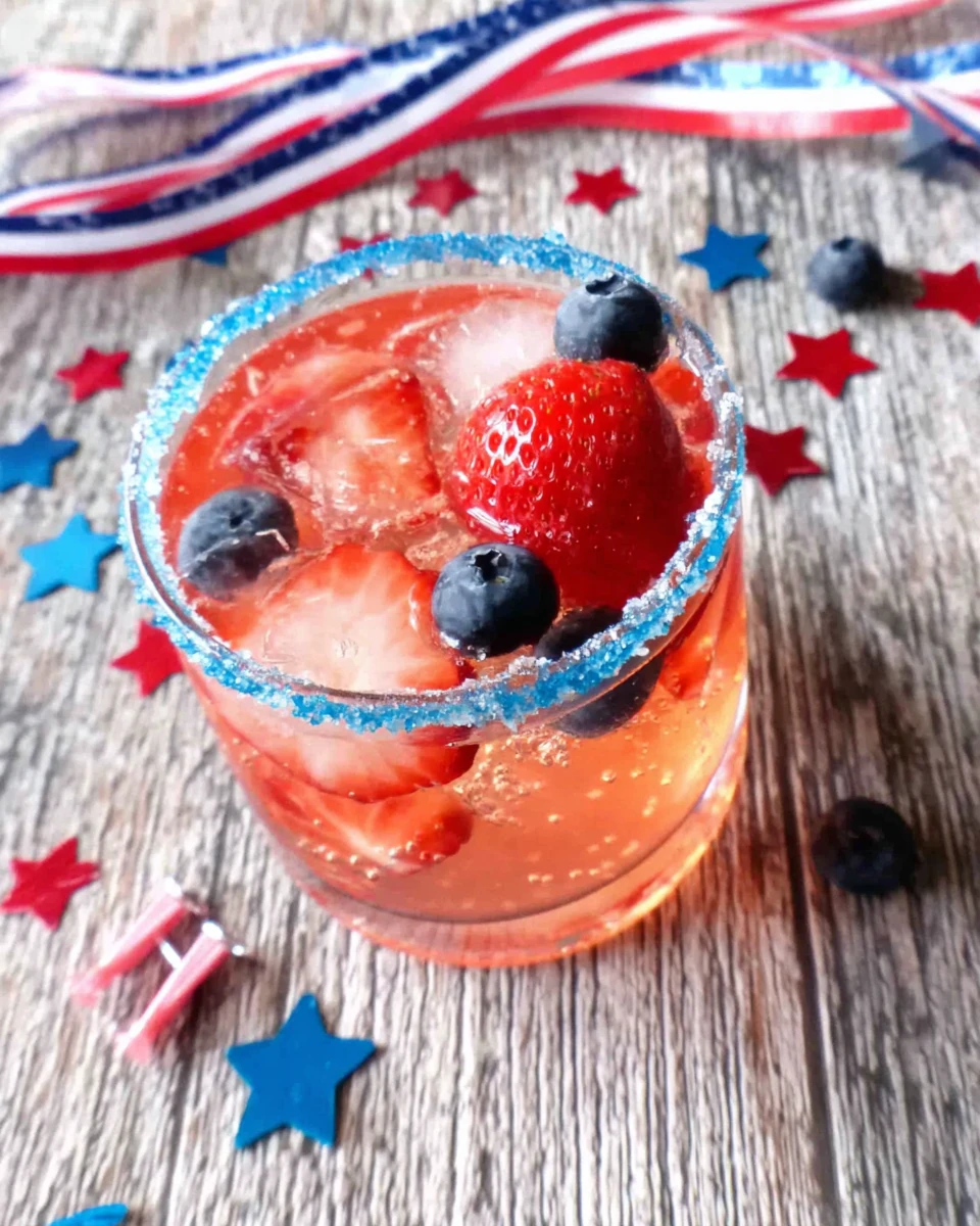 Sparkling vodka cocktail with berries in a glass with blue rim and star decorations