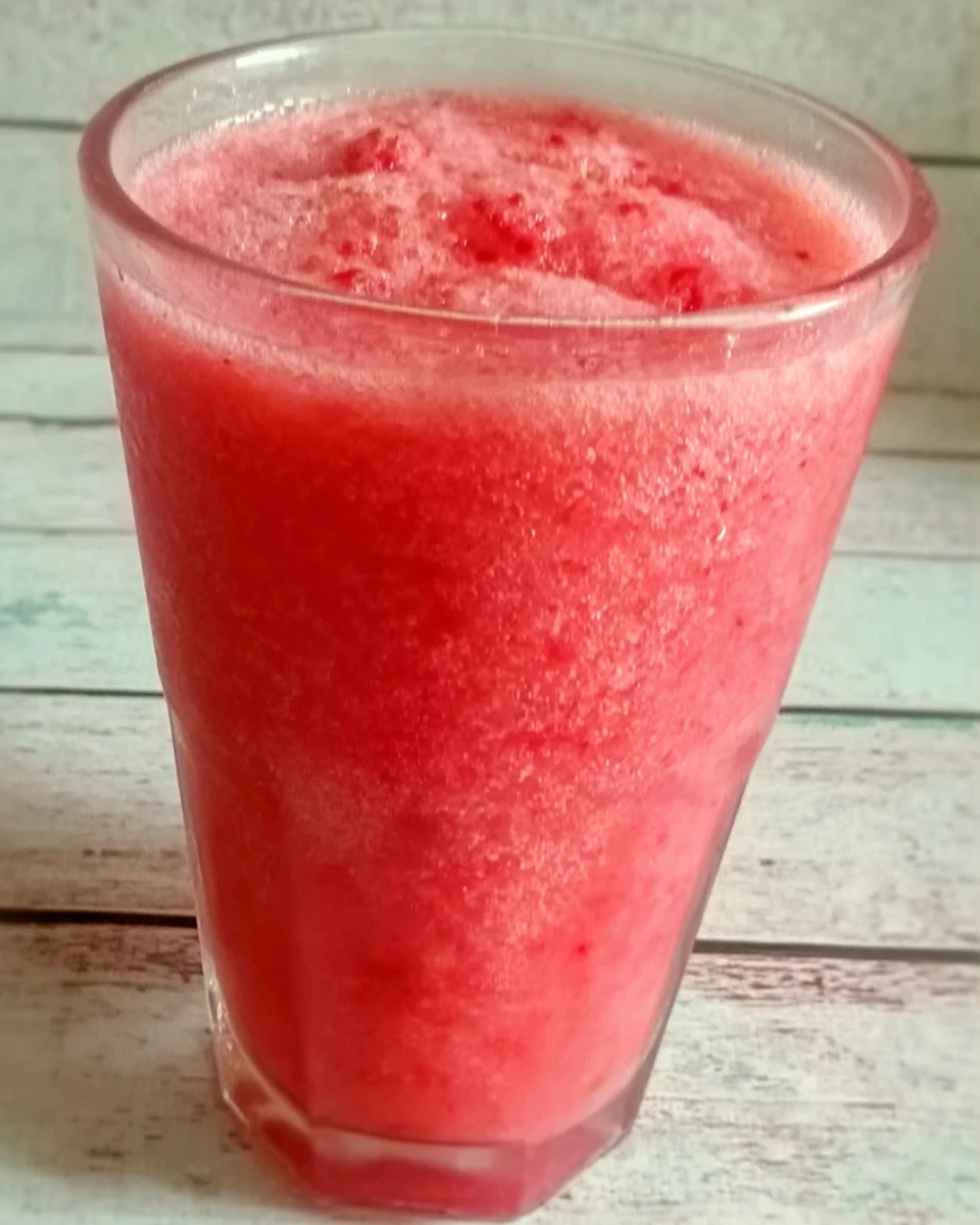 Strawberry smoothie surprise in a glass with condensation, vibrant red color, refreshing and creamy texture.