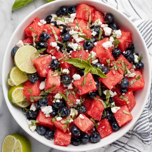 Watermelon blueberry feta salad with fresh herbs and lime in a white bowl