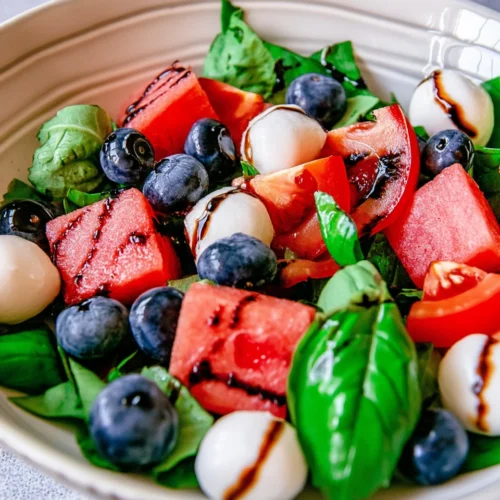Blueberry caprese salad with fresh basil, tomatoes, watermelon, mozzarella, and balsamic drizzle.