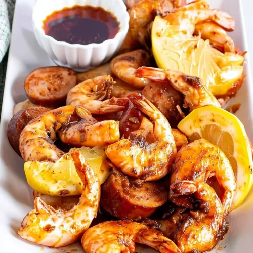 Boiling crab sauce copycat with shrimp, sausage, and lemon on a white plate