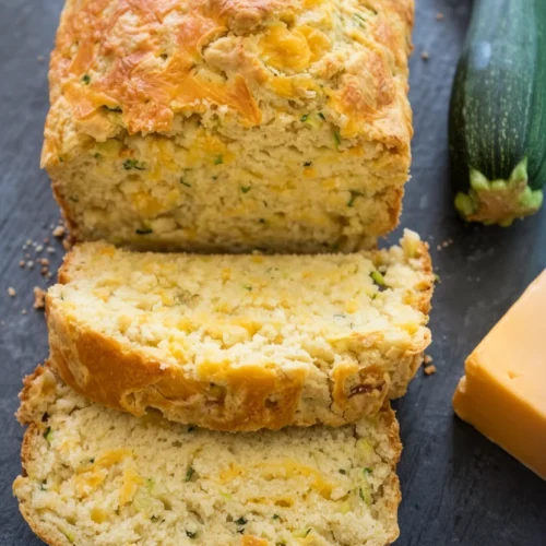 Cheddar Garlic Zucchini Bread: Irresistibly Savory Delight 2 Sliced cheddar garlic zucchini bread with fresh zucchini and cheese nearby