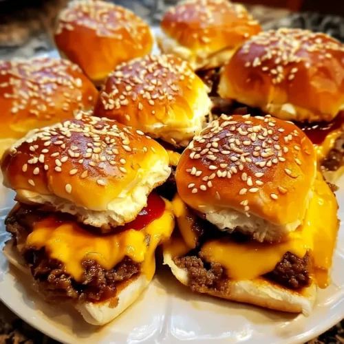 Juicy cheeseburger sliders with melted cheddar and sesame seed buns on a white plate.