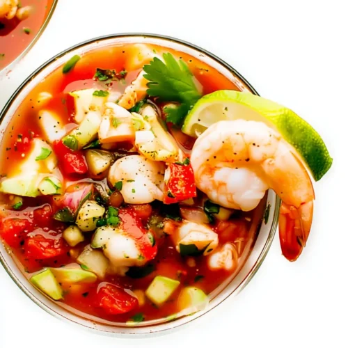 Easy Mexican Shrimp Cocktail: A Refreshing Delight 1 Easy Mexican shrimp cocktail with shrimp, tomatoes, avocado, and lime in a glass bowl