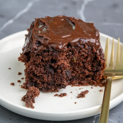 Delicious Gluten Free Chocolate Zucchini Cake Recipe 2 Moist gluten free chocolate zucchini cake slice with chocolate frosting on white plate