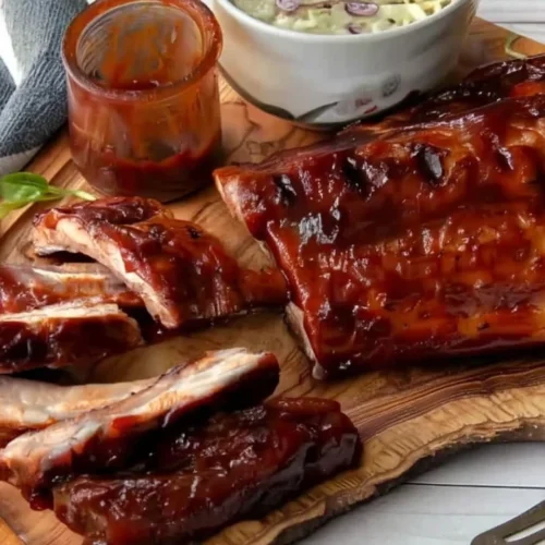 Juicy grilled BBQ spare ribs with BBQ sauce and coleslaw on a wooden board