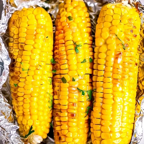 Grilled corn on the cob in foil with butter and herbs