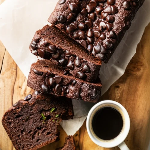 Moist keto chocolate zucchini bread with chocolate chips on a wooden board