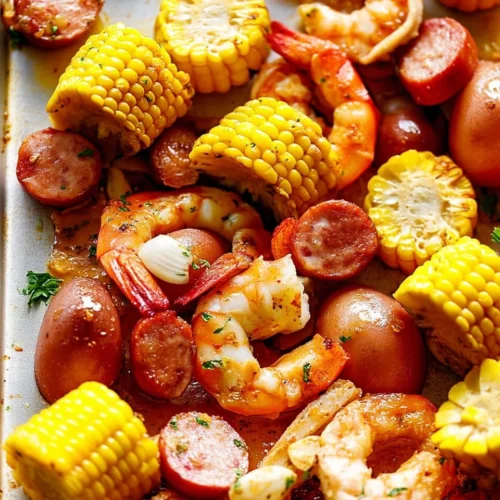 Oven-baked shrimp boil with shrimp, corn, potatoes, and sausage on a baking sheet