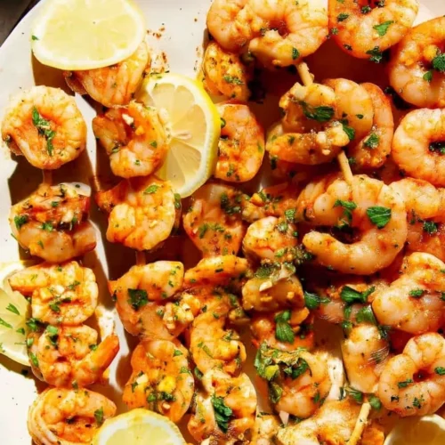 Oven baked shrimp skewers with lemon and parsley on a plate