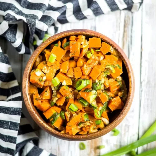 Sweet potato salad in a wooden bowl with green onions and herbs