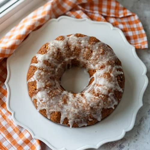 2 ingredient pumpkin spice cake with white icing on a white plate and orange checkered napkin