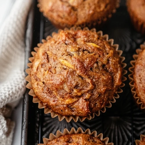 Golden brown sugar breakfast muffins in paper liners on a dark tray
