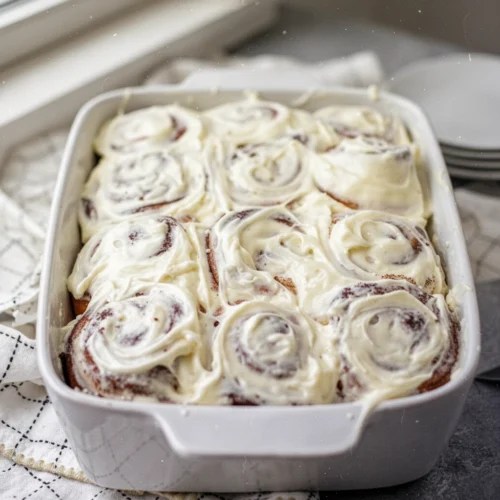 Cinnamon Roll Icing: The Creamiest Delight You'll Ever Make 1 Freshly baked cinnamon rolls with creamy cinnamon roll icing in a white dish