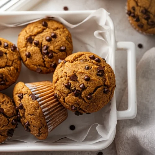 Dairy free pumpkin chocolate chip cookies in a white dish with chocolate chips and milk