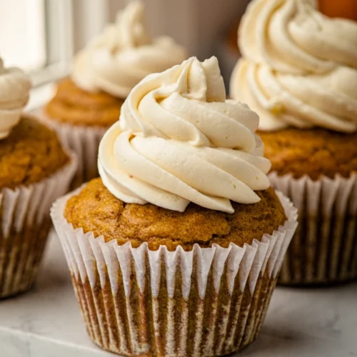 Flourless pumpkin muffins with cream cheese frosting in white liners